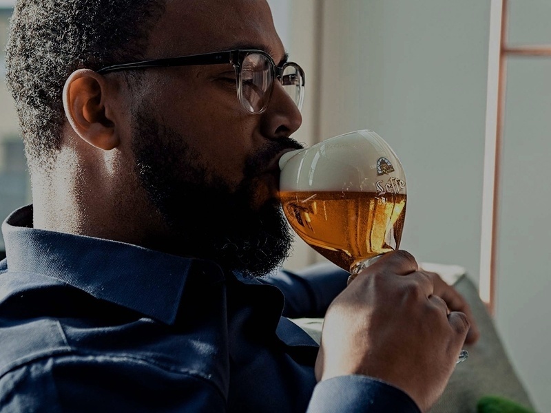 Mann mit Brile trinkt ein Bier